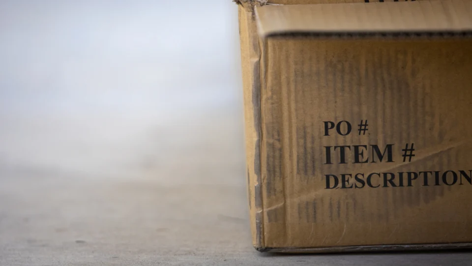 The corner of a cardboard box printed with the headings PO number, item number and description, each with nothing filled in