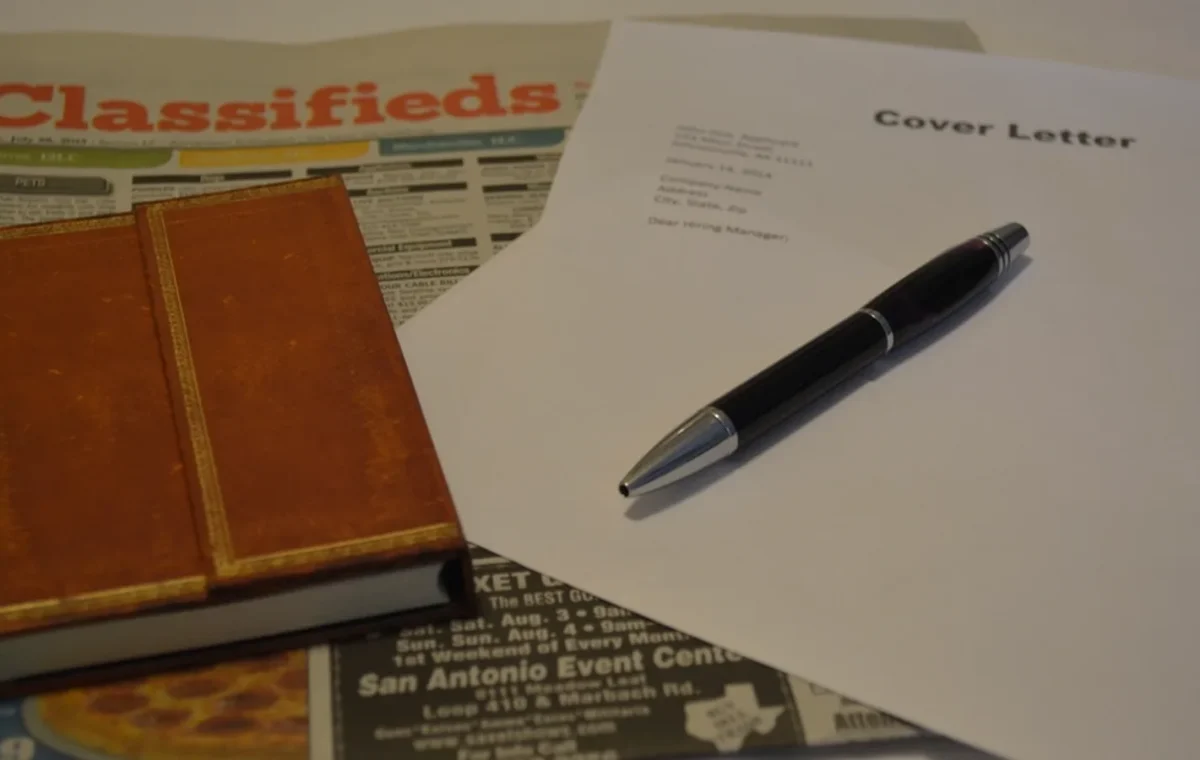 A cover letter, a pen and the classified job adverts on a desk