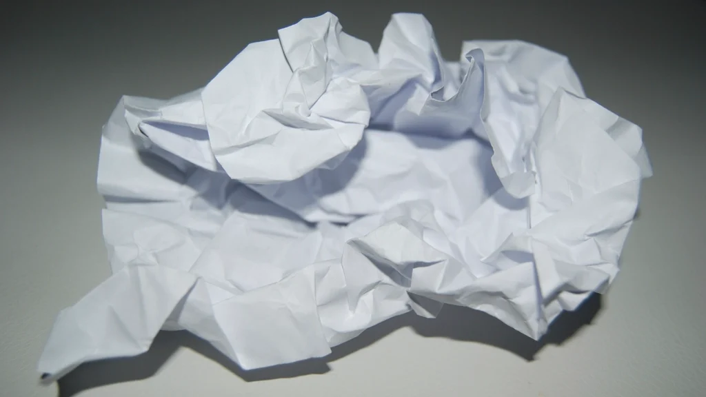 A crumpled sheet of white paper lying on a grey surface