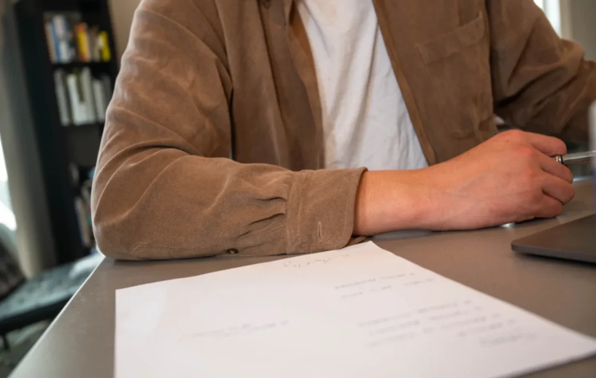 A person at a desk with a pen and a printed form