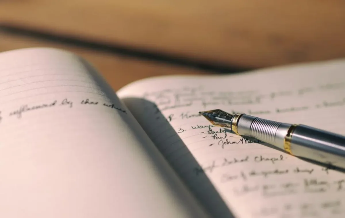 A fountain pen resting on a handwritten page