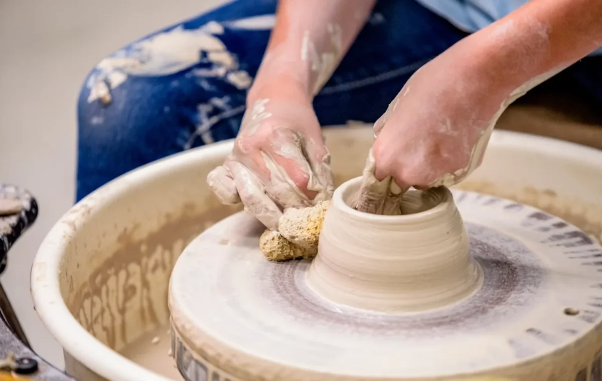 Hands shaping clay on a potter’s wheel