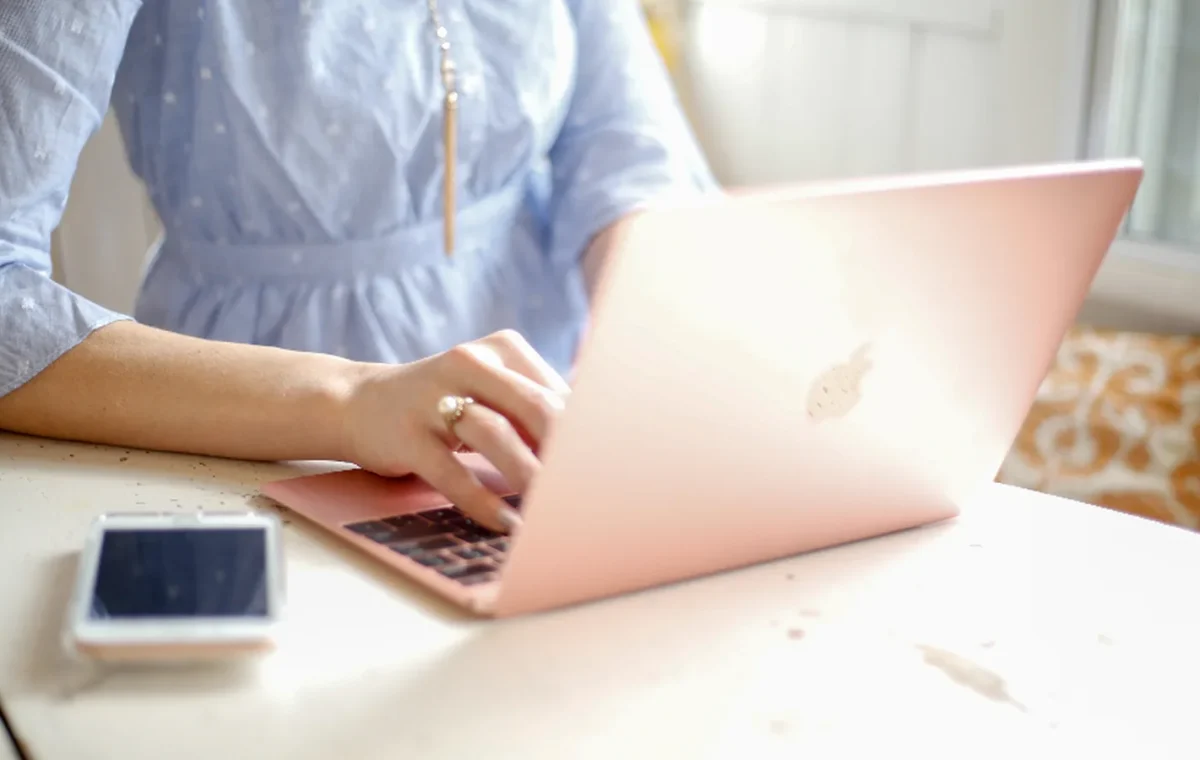 Hands typing on a laptop at a desk